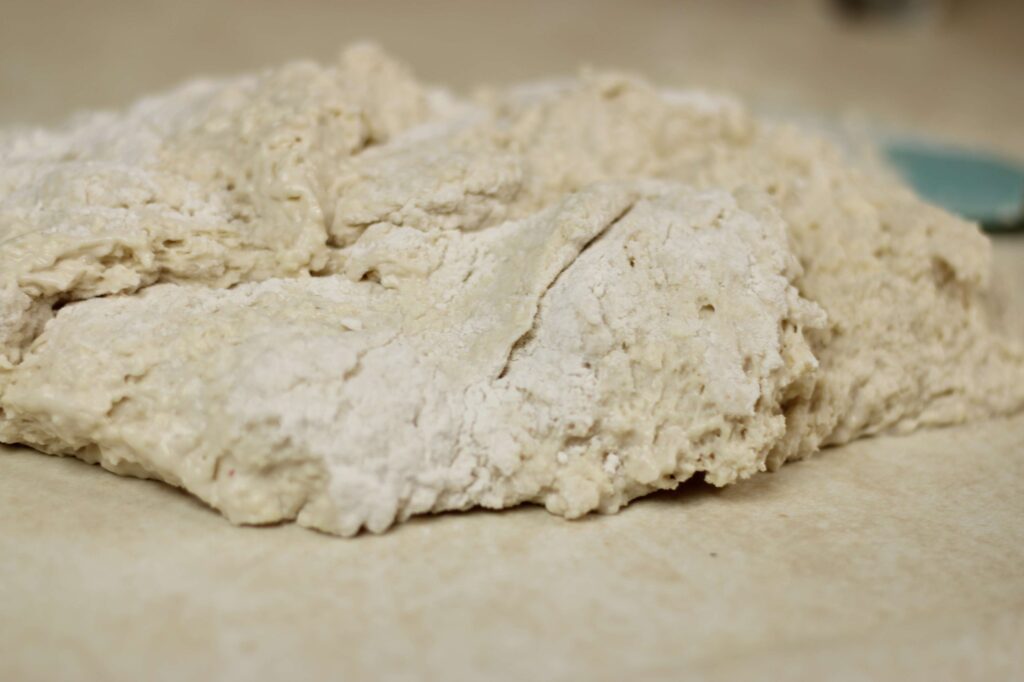 Close up of dough sitting on light colored counter.