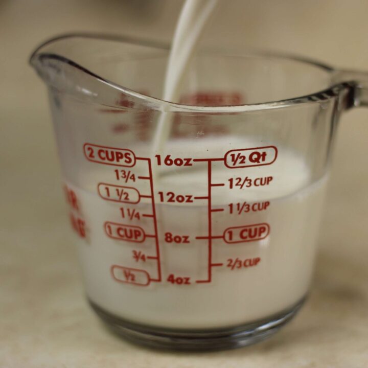 milk being poured into glass measuring cup