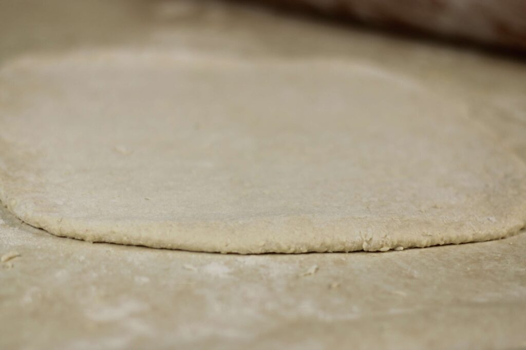 Close up of rolled out dough on a light color counter.