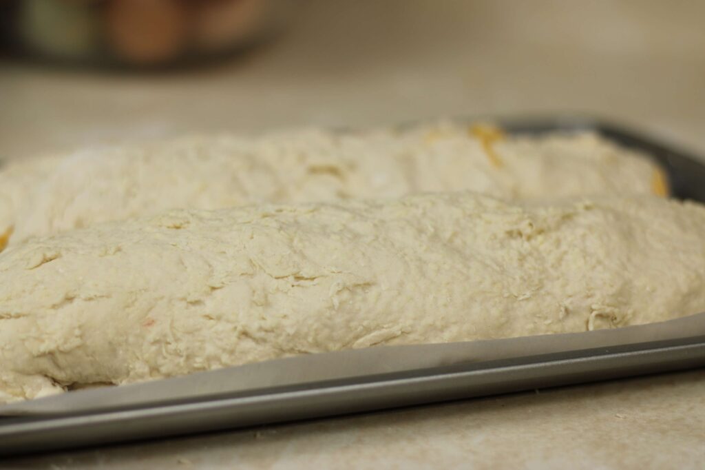 Close up of two cylindrical shaped rolls on baking sheet.  