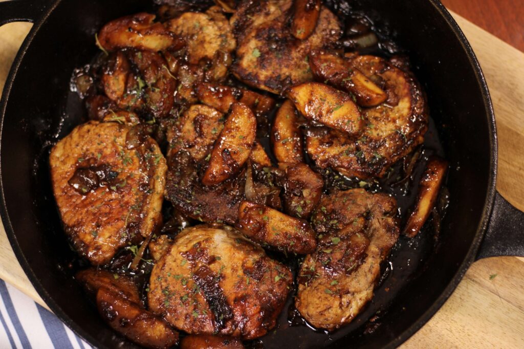 cooked porkchops and apples on a cast iron skillet 