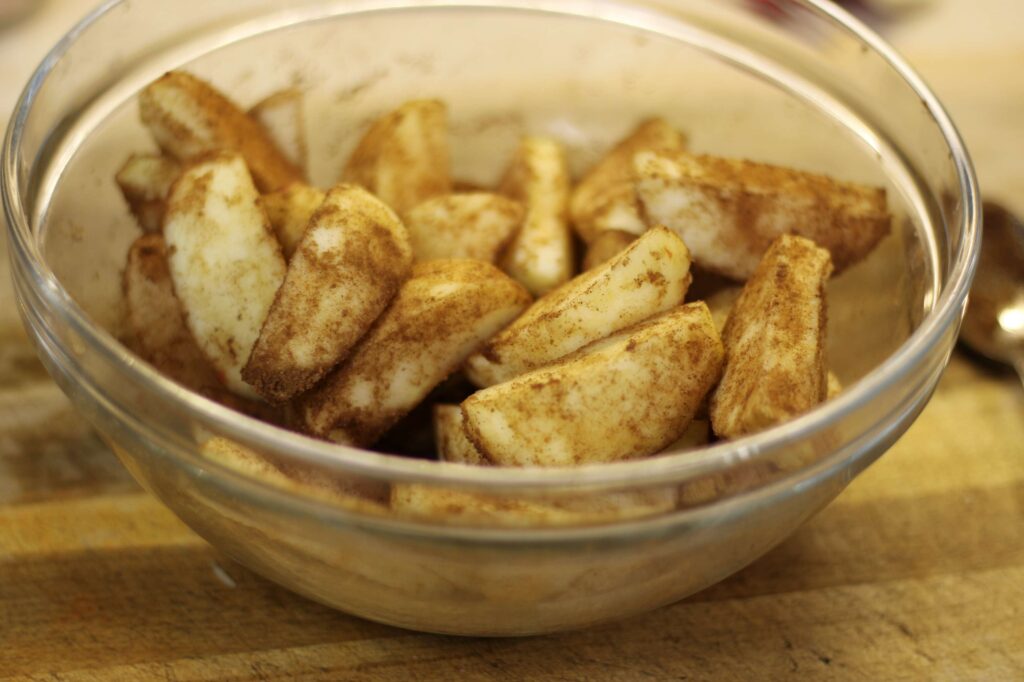 apple slices on a glass bowl covered with brown sugar and cinnamon