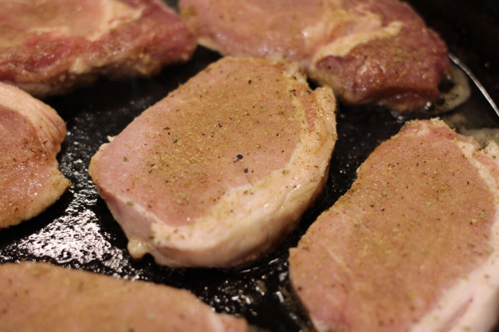 caramel apple pork chops browning in a cast iron skillet