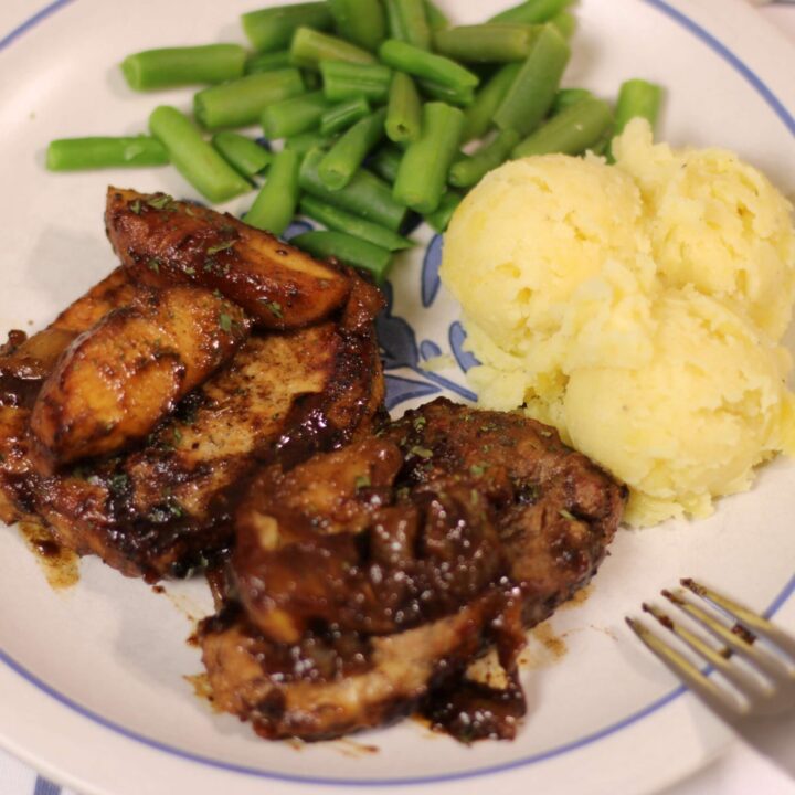 plated caramel apple pork chops with sides of potatoes and green beans