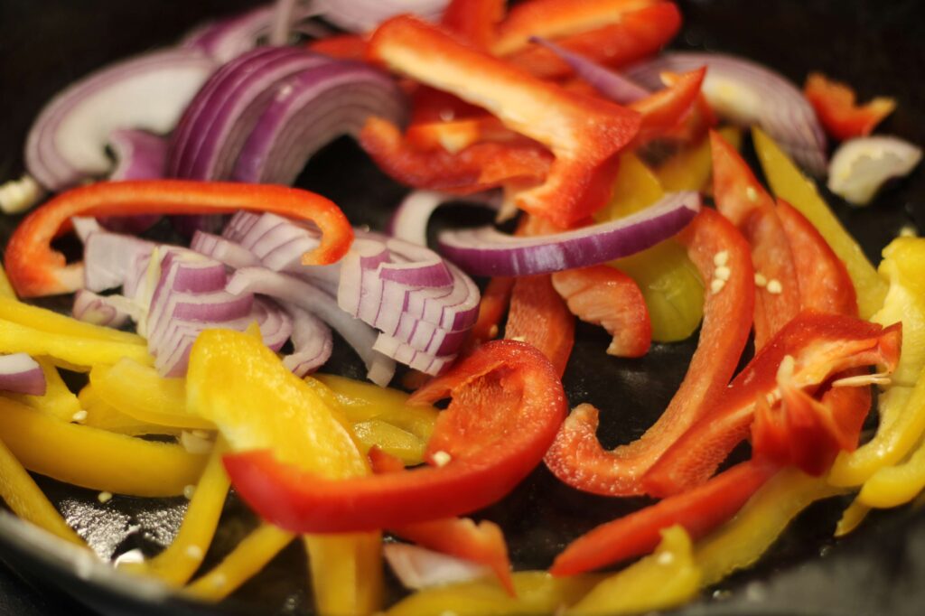 red onions and red and yellow peppers on cast iron skillet