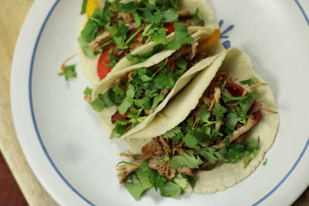 three pork carnitas tacos with cilantro