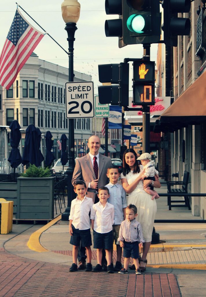 Picture of family, dad mom and 5 boys in front of a crossing light.