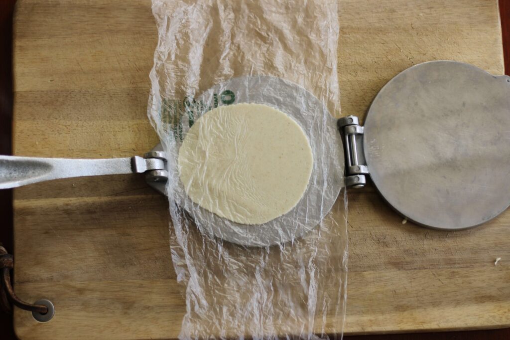 open tortilla press with a freshly pressed corn tortilla