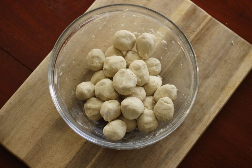 large glass bowl containing masa dough balls for homemade corn tortillas