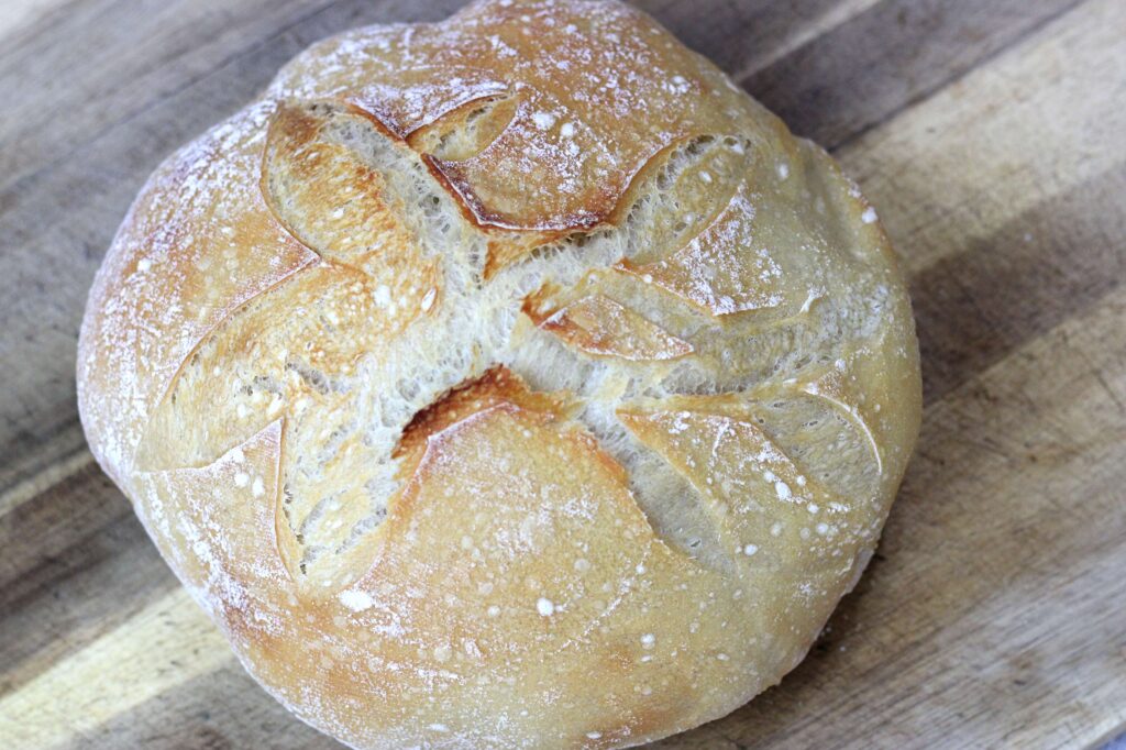 Freshly baked sourdough boule on wood cutting board