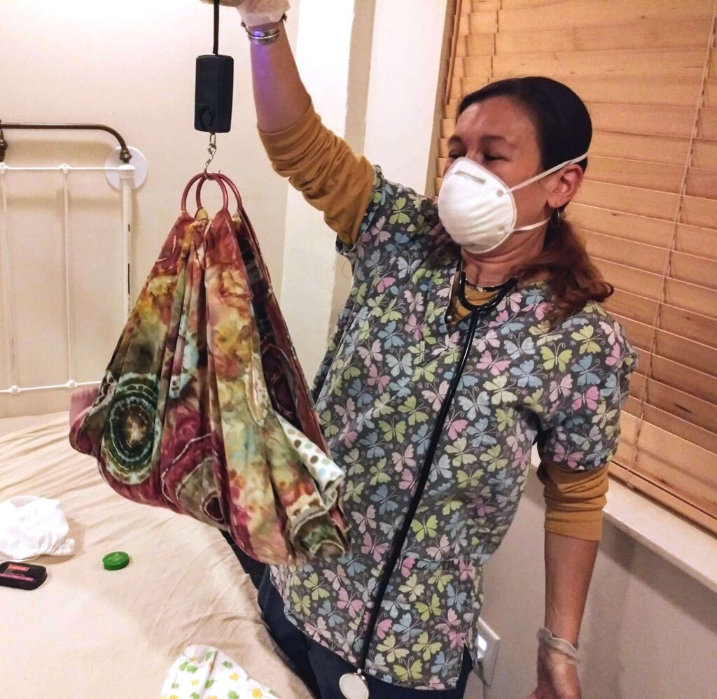 midwife weighting newborn after natural birth 