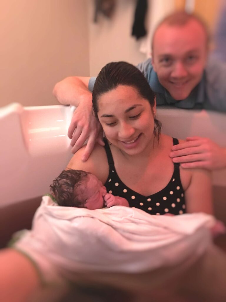 woman holding newborn in birthing tub 