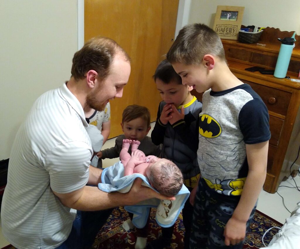 Dad showing siblings new baby for the first time just hours after homebirth 