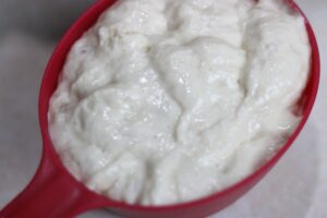 close up of sourdough starter in a measuring cup