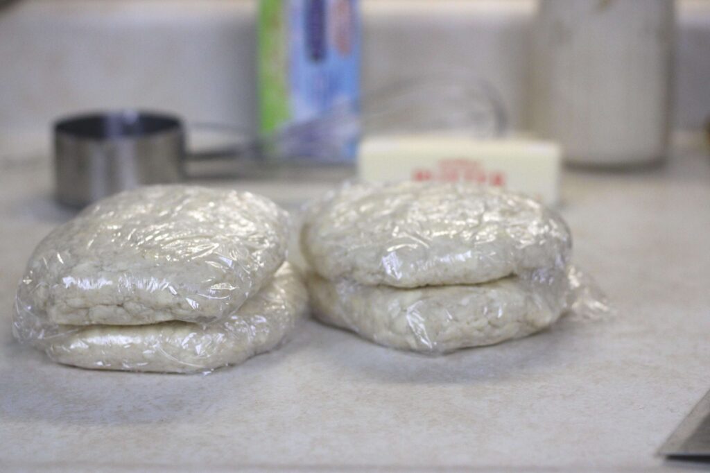 four pieces of all-butter pie crust wrapped in saran wrap ready to be chilled