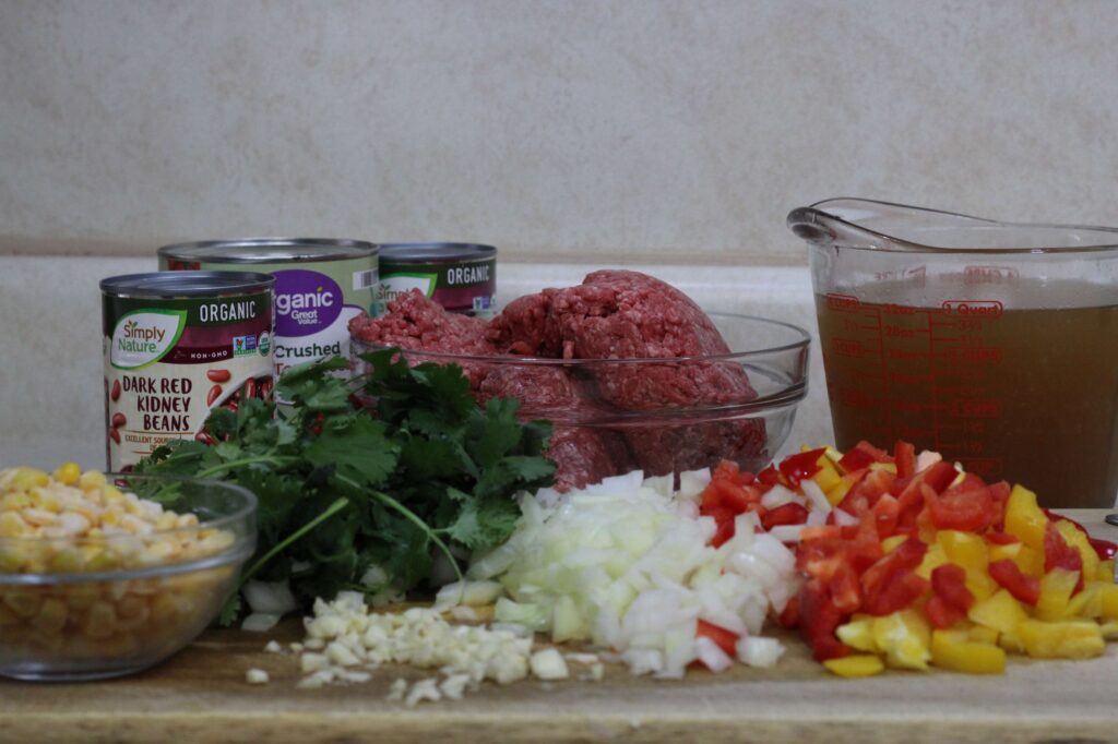 ground beef, chopped onions, bell peppers, garlic, corn, cilantro, broth, can of crushed tomatoes and two cans of beans 