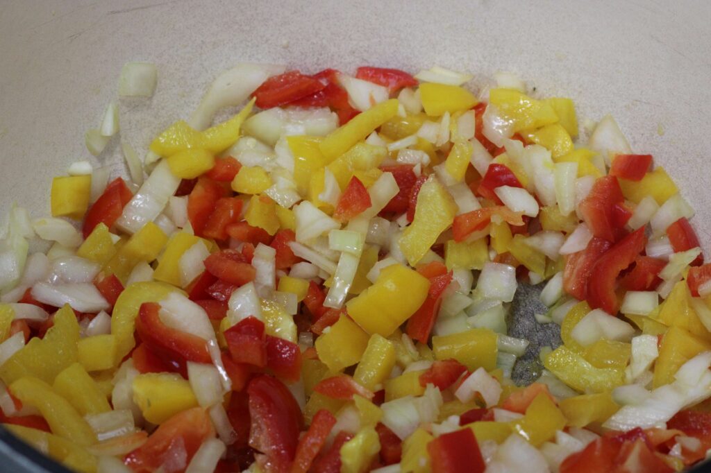 diced onion, peppers and garlic cooking in dutch oven 