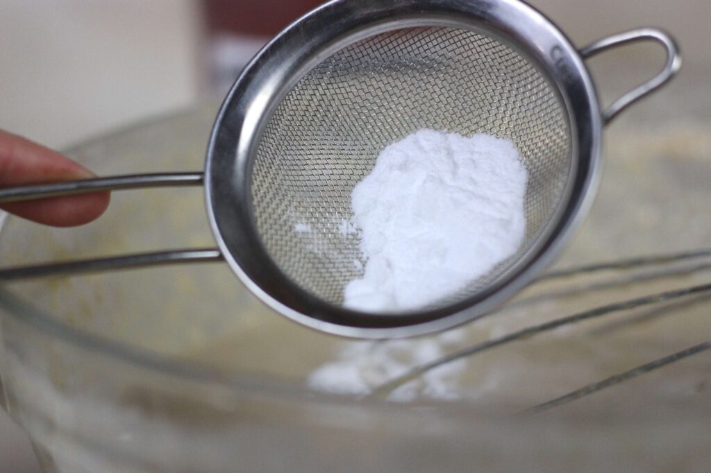 baking soda being sifted into sourdough pancake batter 