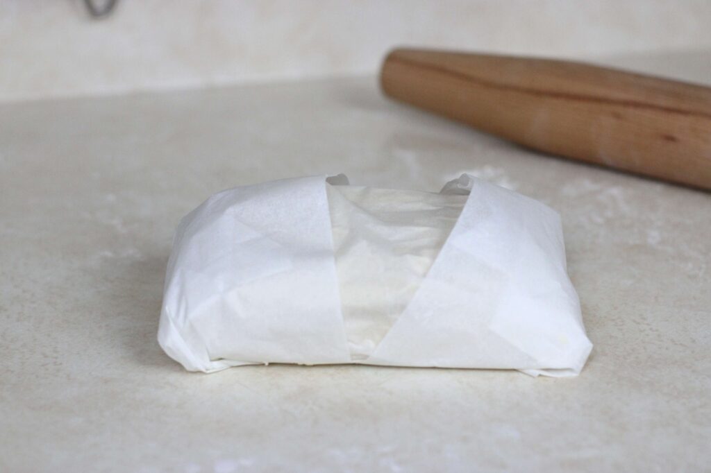 pastry dough wrapped up in parchment paper ready for second rise in the fridge 