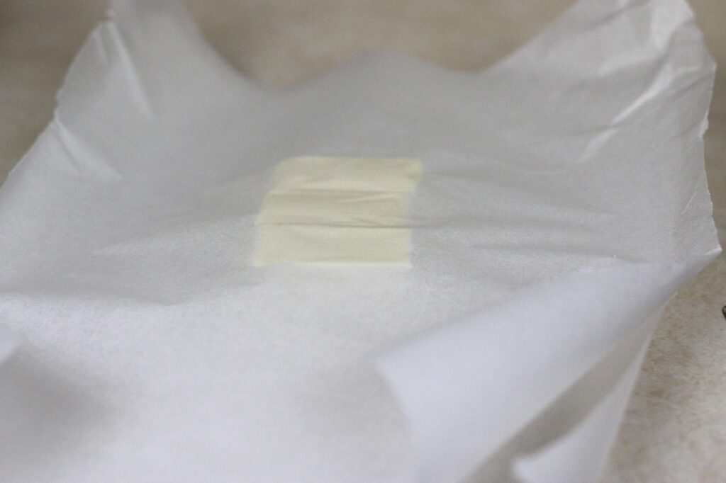 butter in between two pieces of parchment paper 