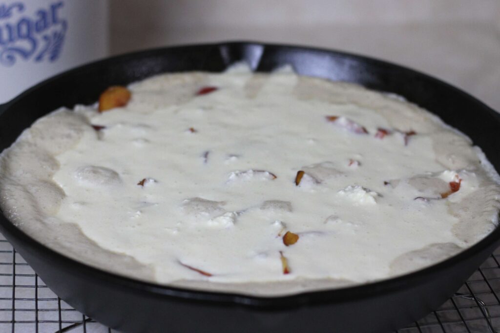 unbaked sourdough peaches and cream dump cake in cast iron skillet 