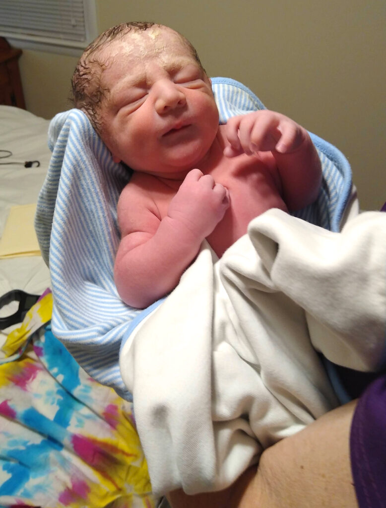 an hour old newborn with vernix on his forehead 