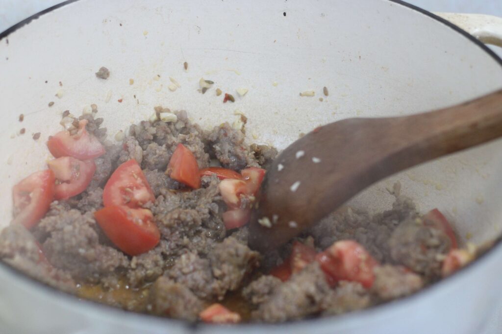 sausage. tomatoes and garlic sauteing in pot for soup