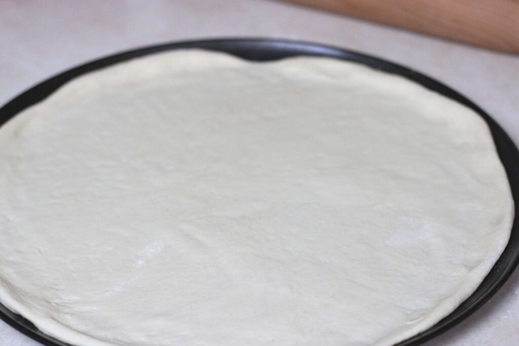 rolled out sourdough pizza dough on pizza pan