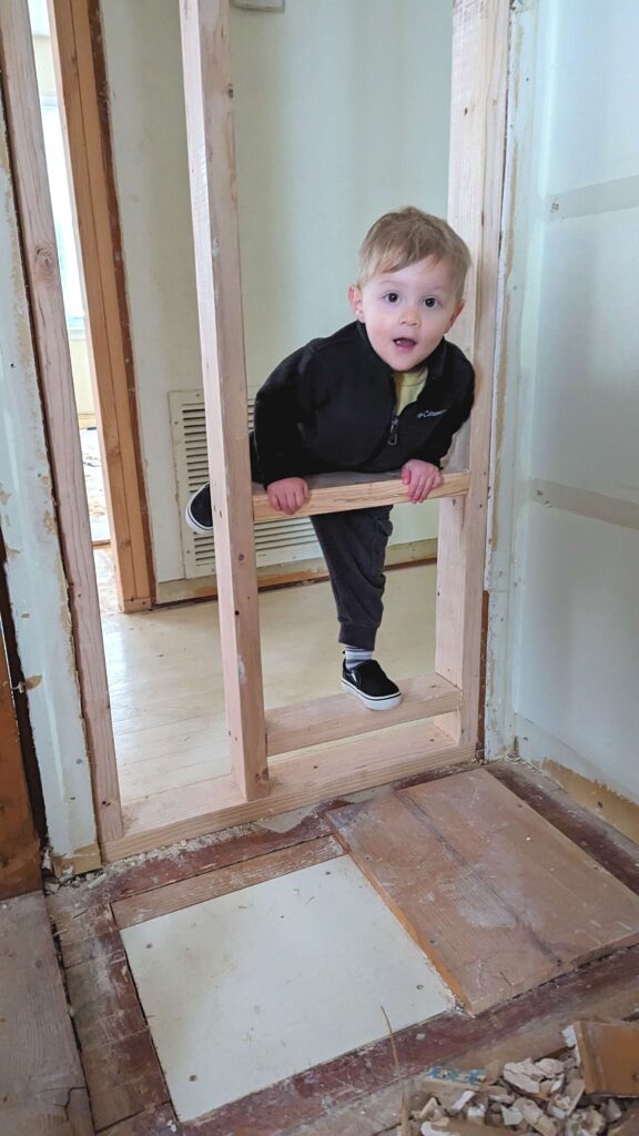 small child playing on expose wall studs 