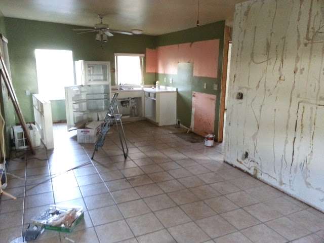 progress shot of home remodel, exposed glue from wood paneling on walls and mostly gutted kitchen