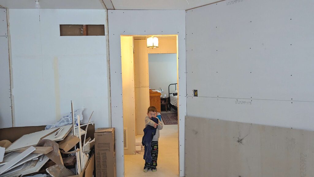 little kid at the doorway of a room being remodeled remodeling with kids