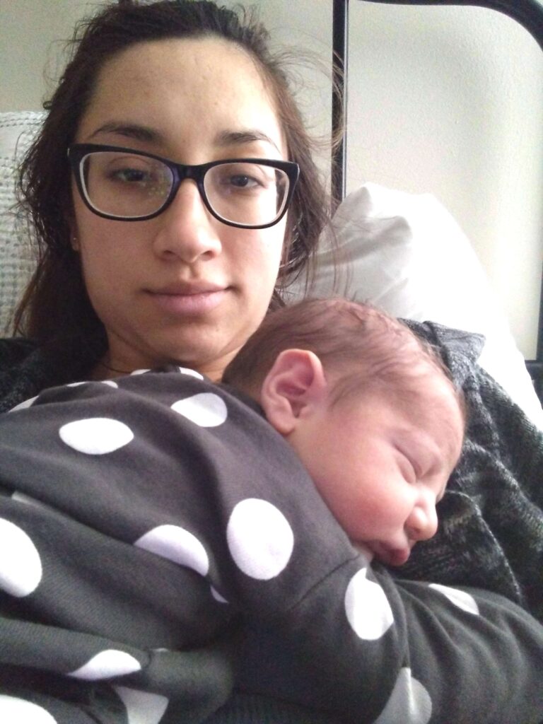 woman wearing glasses looking tired 24 hours postpartum with newborn