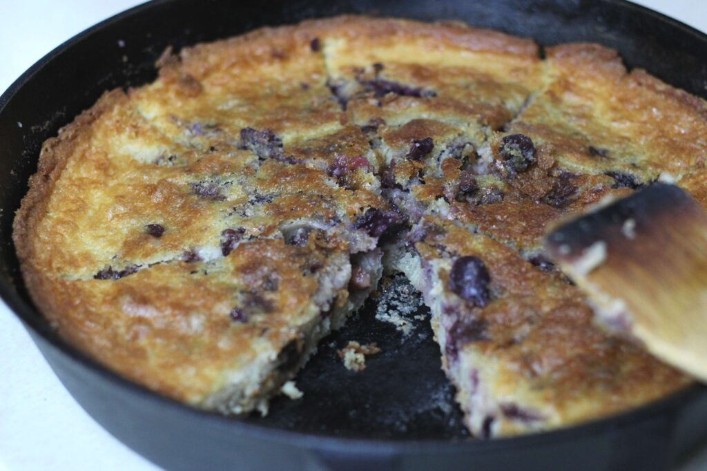sourdough discard cherry cobbler in cast iron skillet with a piece cut out