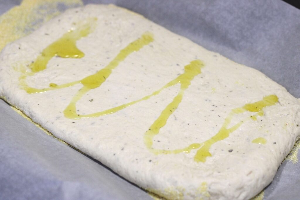pizza dough on tray drizzled with olive oil