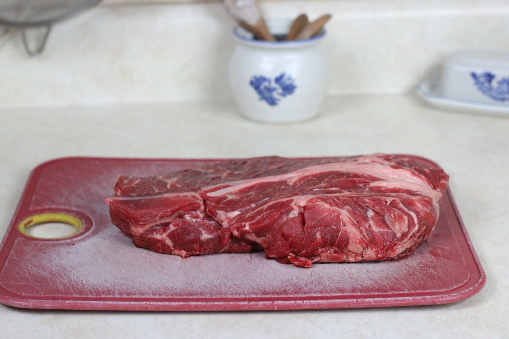 large piece of beef chuck roast on cutting board 