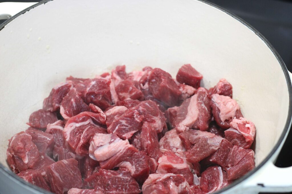 raw stew meat pieces in dutch oven 
