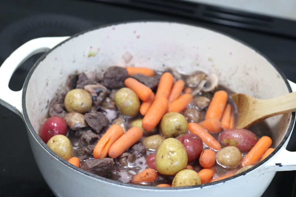 potaoes and carrots dded to a boeuf bourguignon pot