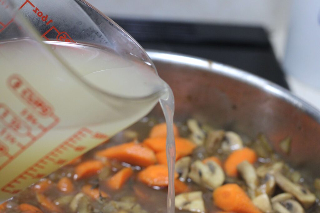 chicken broth being added to chicken fricassee sauce mid cooking process