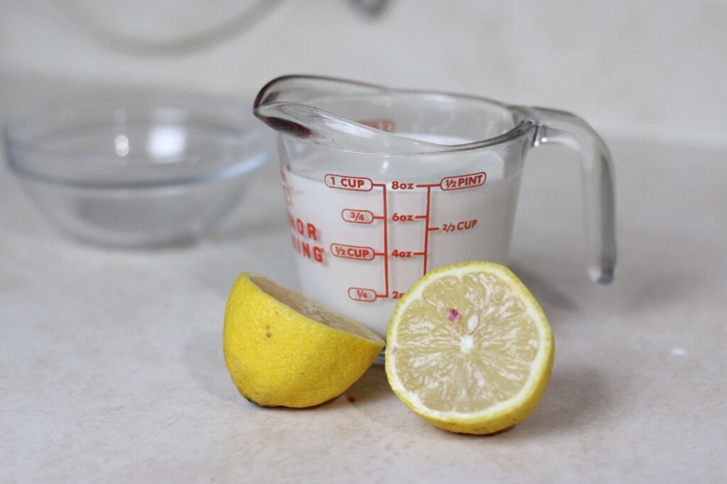 heavy cream in measuring cup along side a lemon cut in half