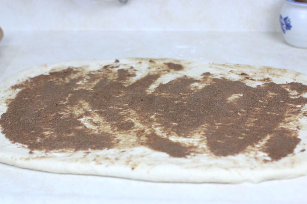 cinnamon butter spread on dough for cinnamon rolls