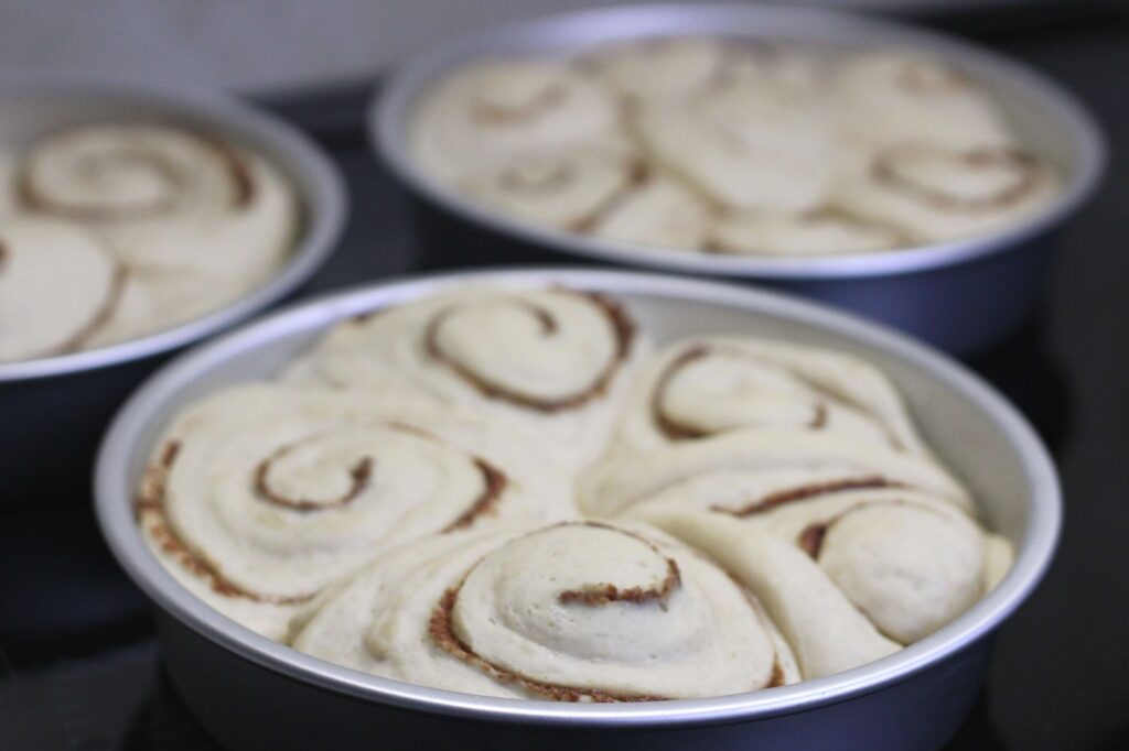 sourdough cinnamon rolls in cake pans ready to be baked 